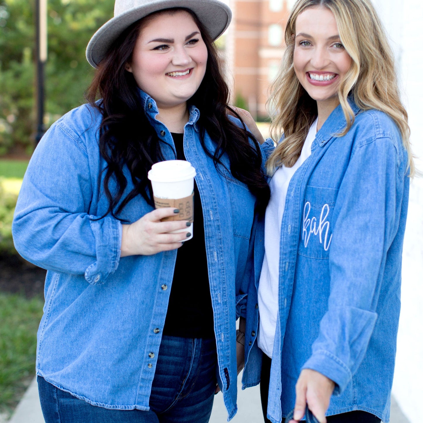 a brunette and blonde woman standing side by side wearing button down light denim shirts with custom embroidered pockets