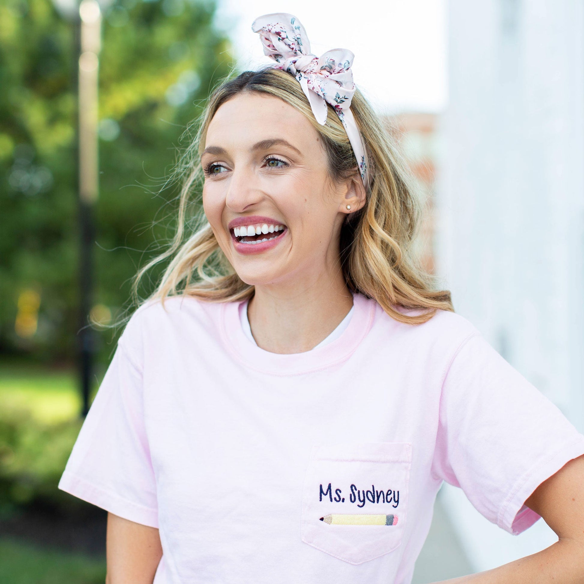 young female teacher wearing light pink embroidered pocket crewneck tee shirt with yellow pencil and personalization above