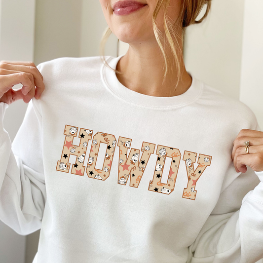 girl wearing a white sweatshirt with a large HOWDY print with a ghost cowboy pattern