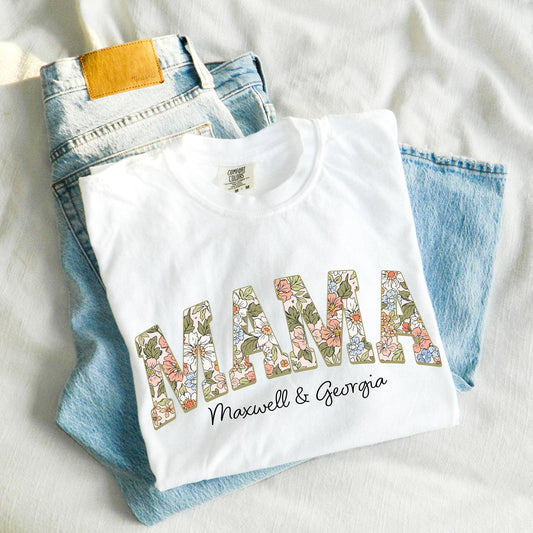 image of a pair of jeans with a folded white comfort colors t-shirt with MAMA in a pastel boho floral print and custom children's names underneath