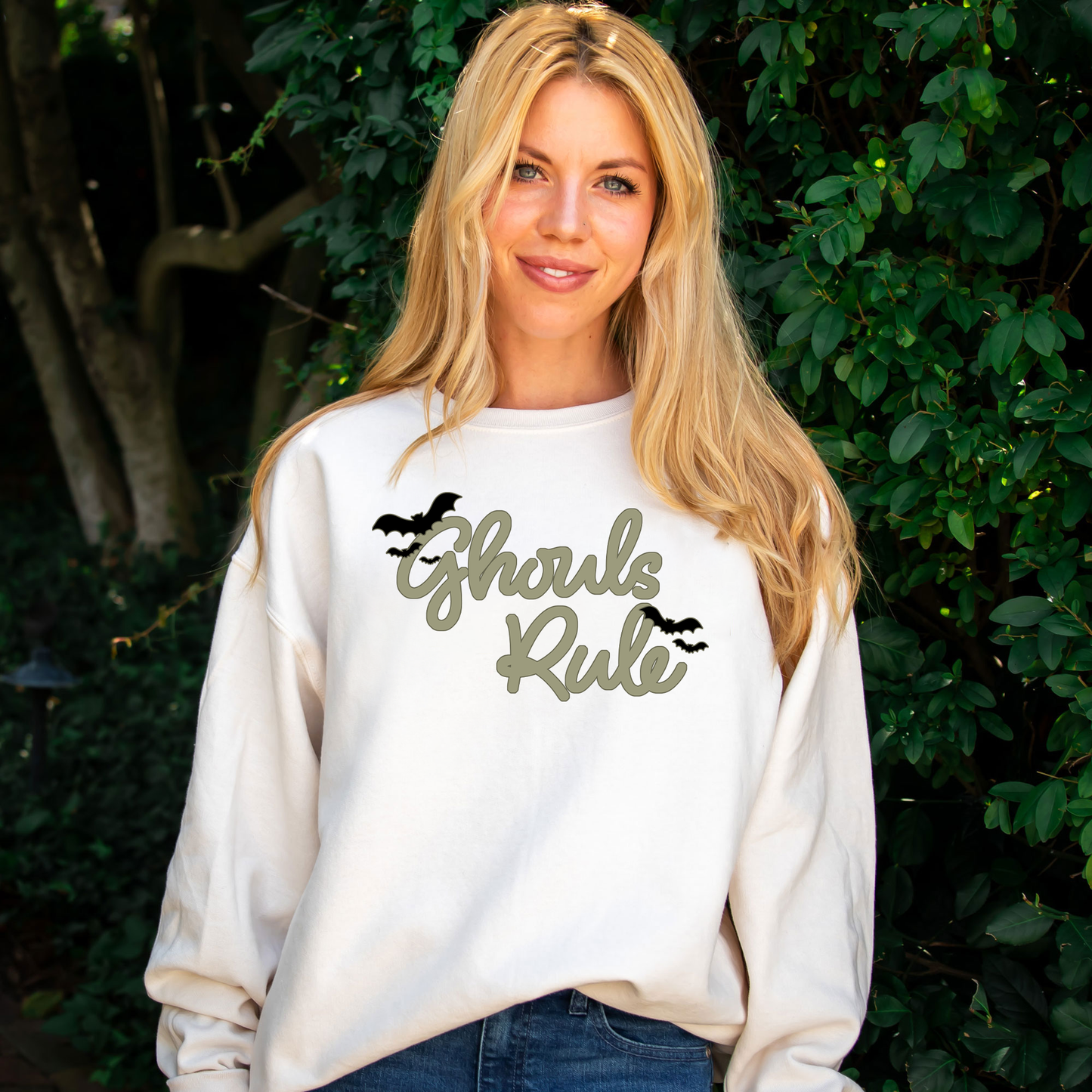 woman wearing an oversized cream sweatshirt with a cute ghouls rule print with bats