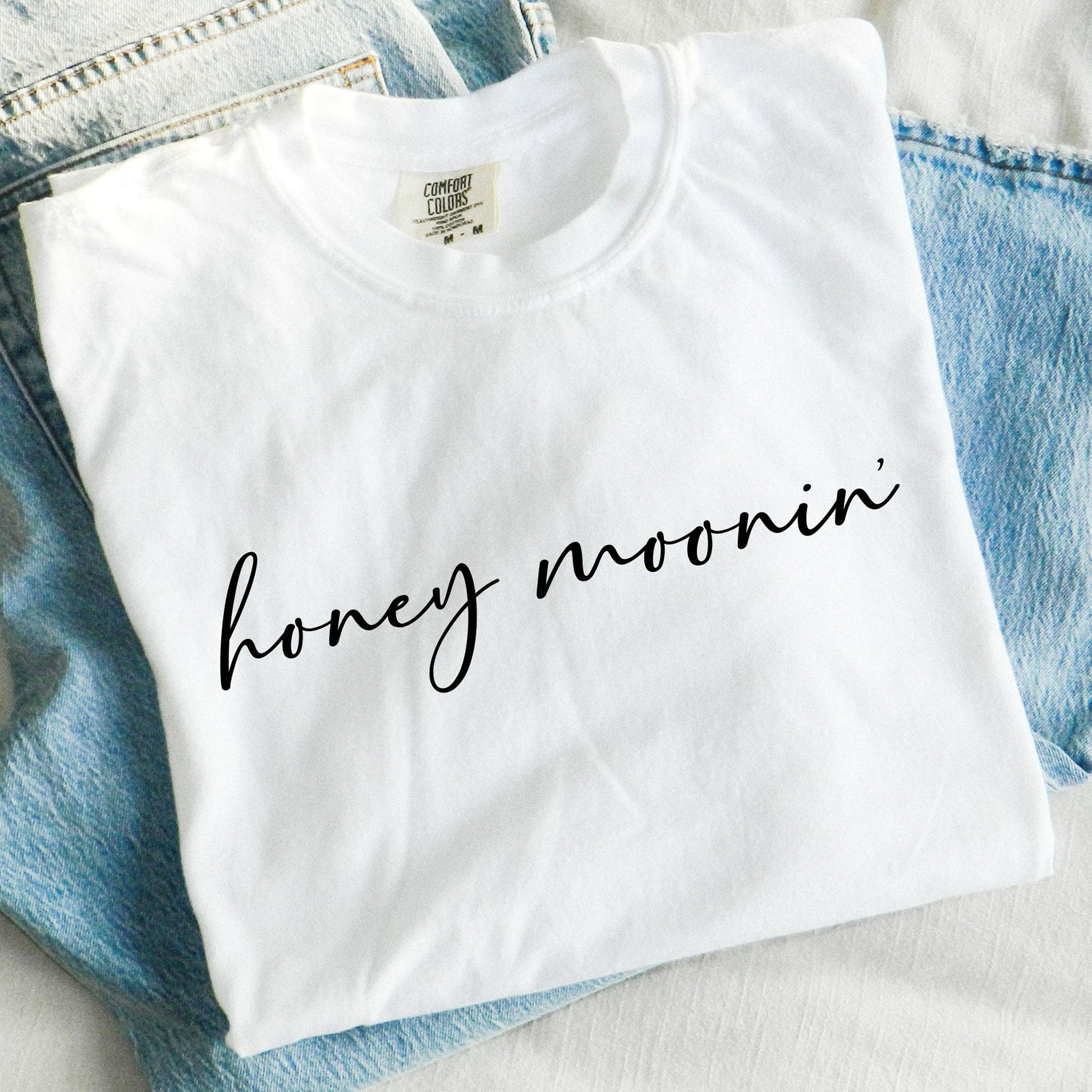 white comfort colors t-shirt with honey moonin' printed across the chest in a black script font