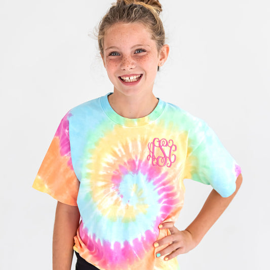 Young girl wearing a colorful pastel tie dye t-shirt with a personalized embroidered monogram in pink thread on the left chest