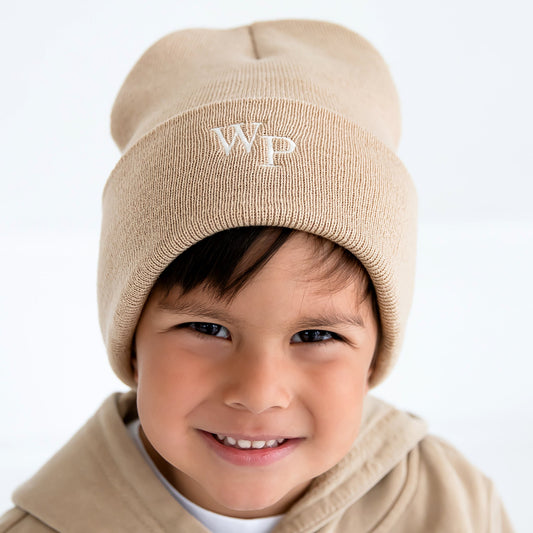 little boy wearing a camel beanie winter hat with a custom two letter monogram embroidered on the front cuff