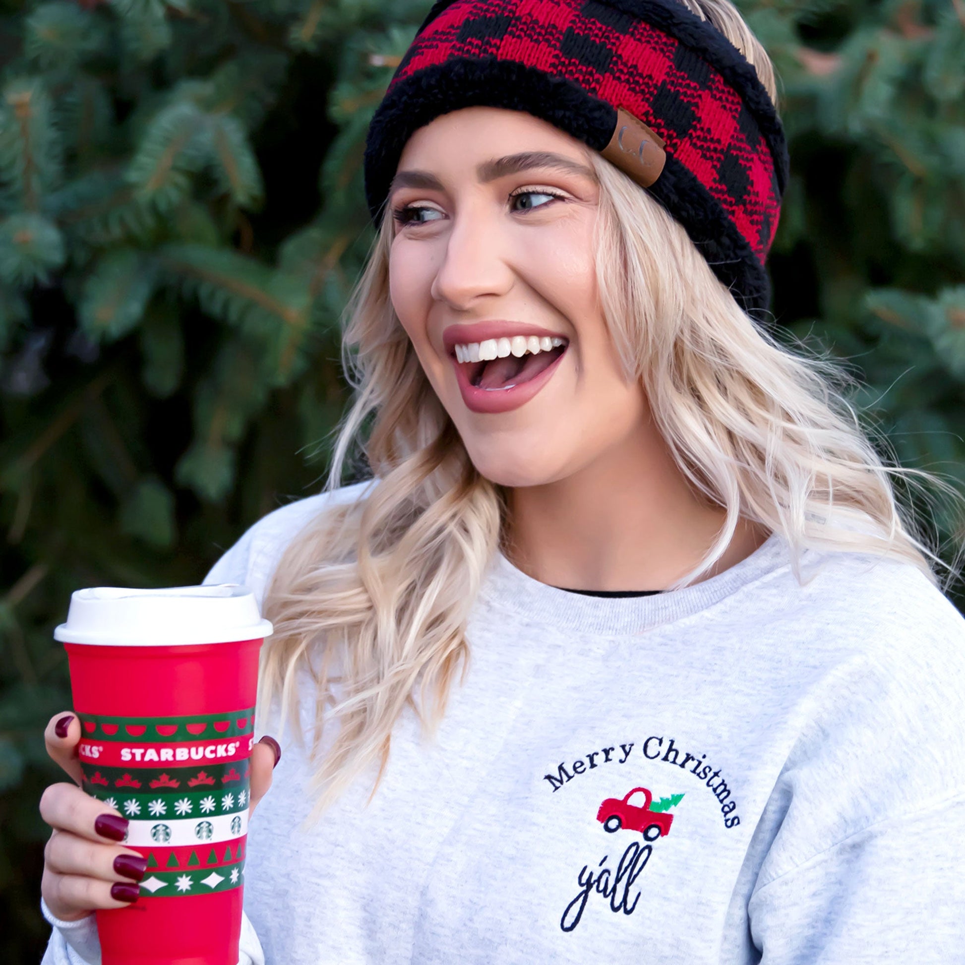 woman with blonde hair with beanie holding coffee cup wearing ash crewneck with merry Christmas y'all and red truck embroidered