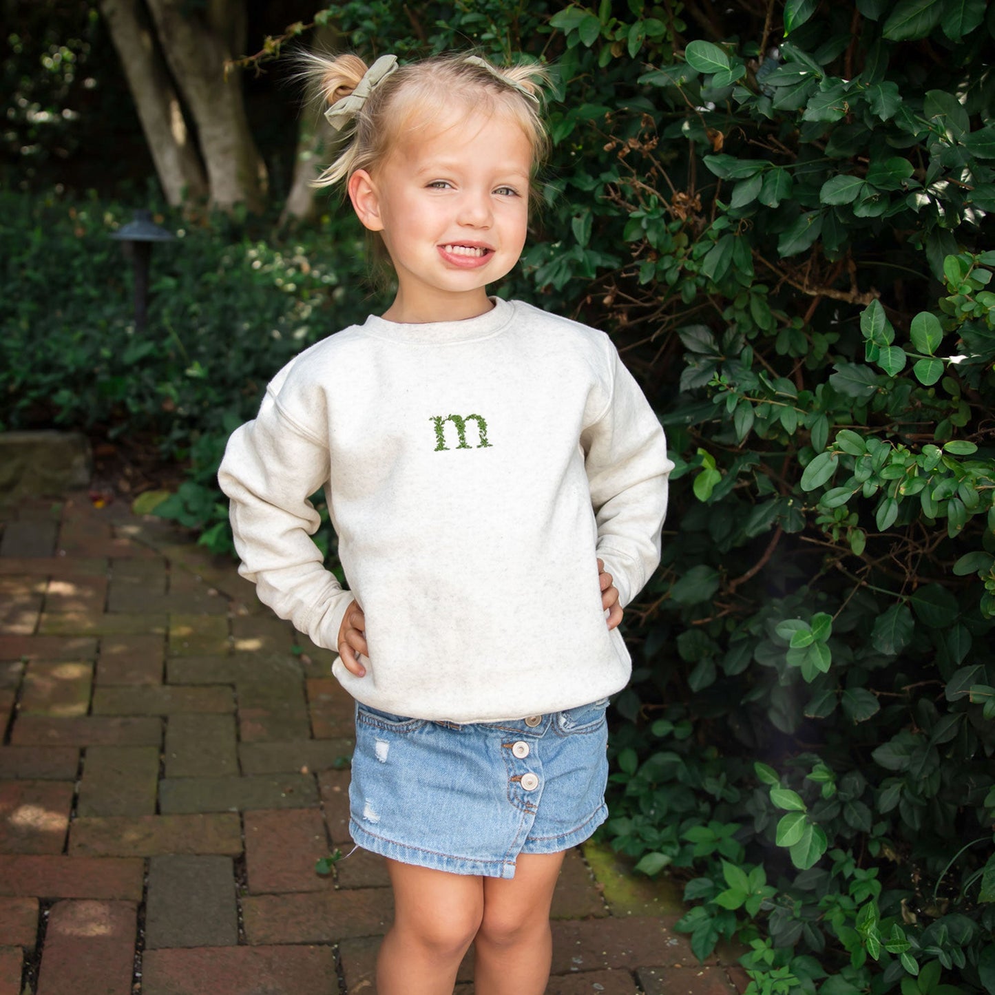 Toddler girl wearing a crewneck sweatshirt with a custom floral initial embroidered center chest