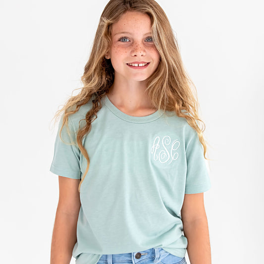 young girl wearing a heather dusty blue tee with monogram embroidered in a white thread