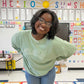 teacher in her classroom wearing a sage waffle knit crew with embroidered TEACH design