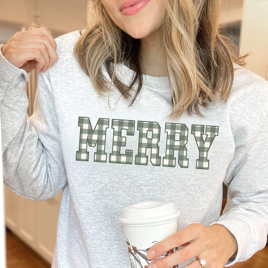 woman wearing an ash gray crewneck sweatshirt featuring a dtg printed MERRY design in a green and cream plaid pattern