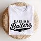 Image of a white t-shirt featuring a 'raising ballers' t-shirt in a sporty varsity mixed font