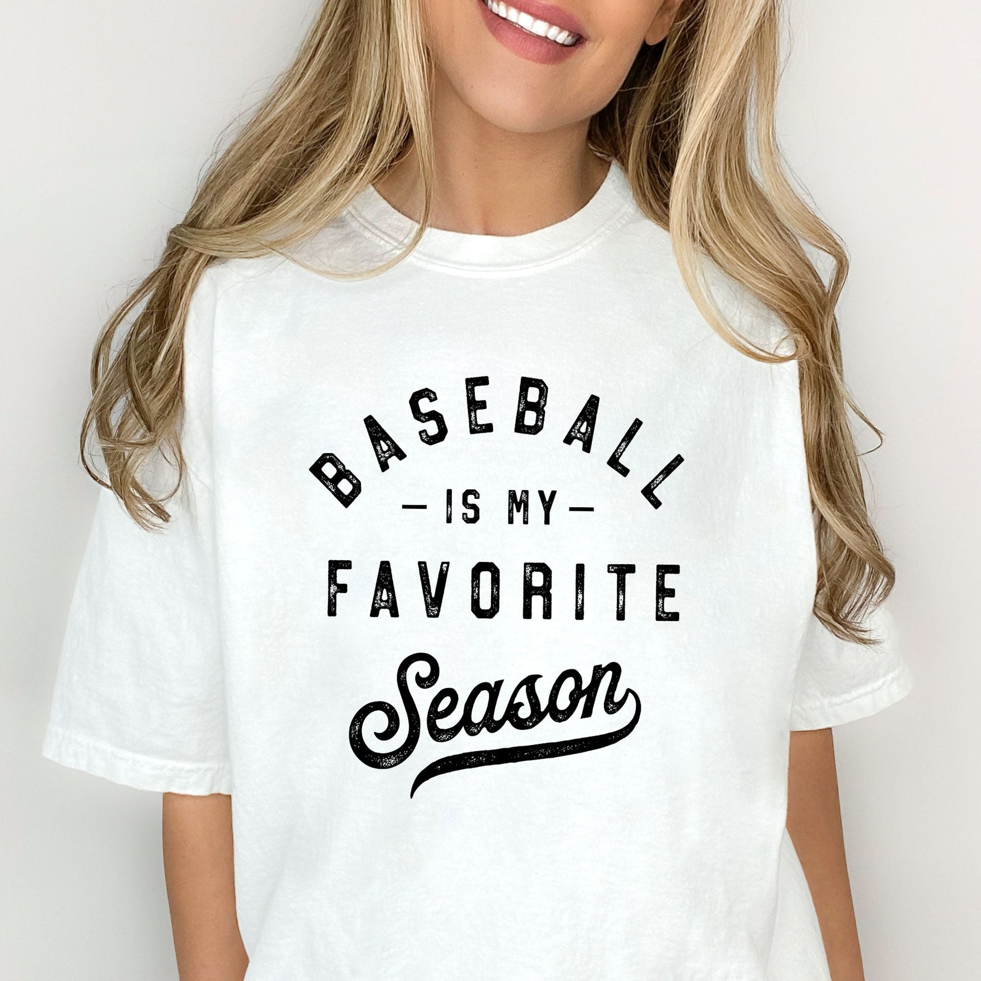 woman wearing a white t-shirt featuring a distressed dtg print reading 'baseball is my favorite season'