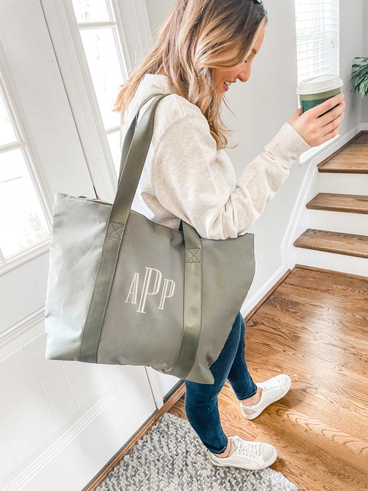 woman standing in foyer with a olive monogramed tote bag