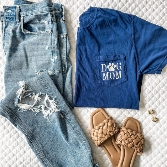 flatlay of outfit featuring distressed jeans, sandals, and navy blue comfort colors tee with dog mom embroidered on the pocket 