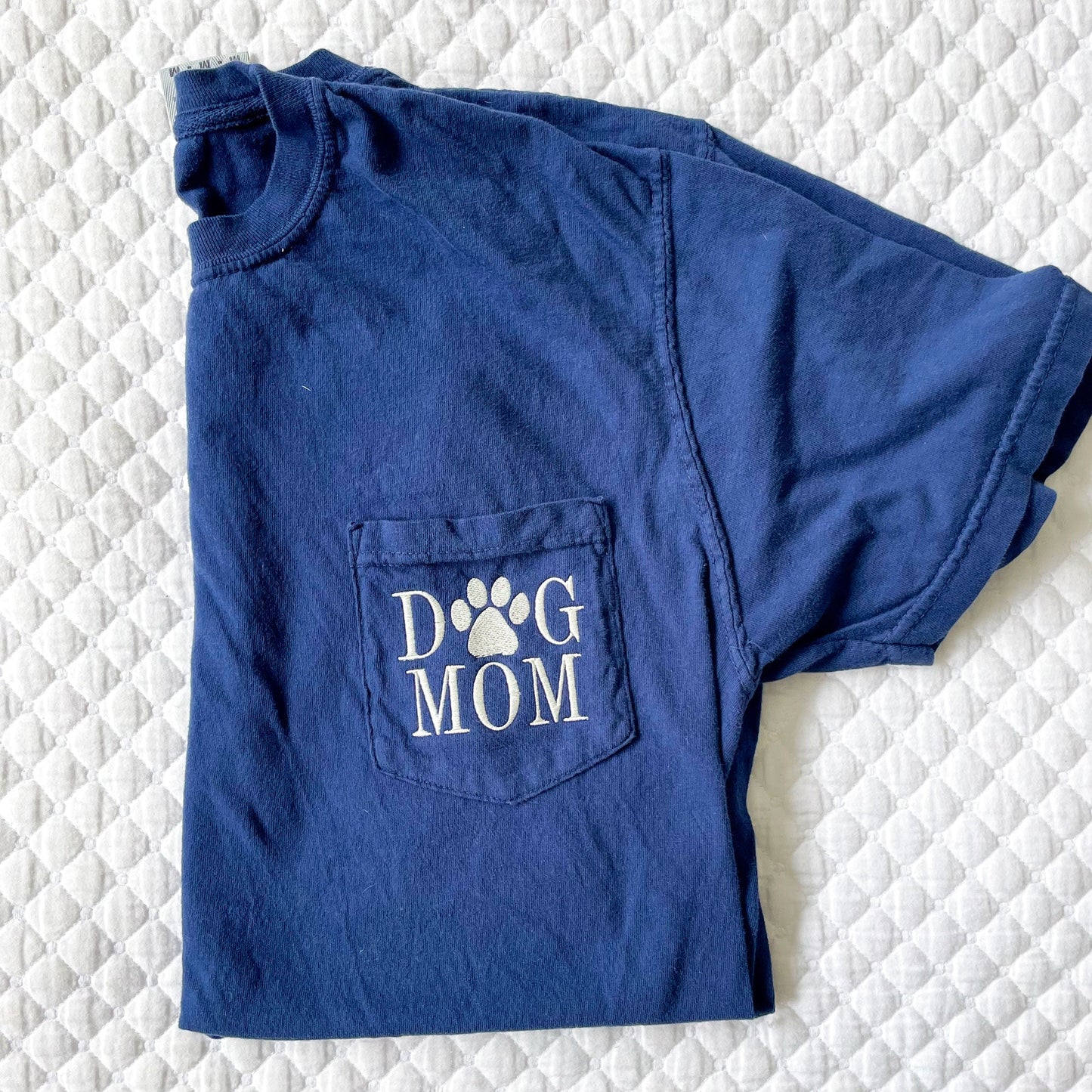 close up of navy blue comfort colors tee with dog mom embroidered in natural thread on the pocket