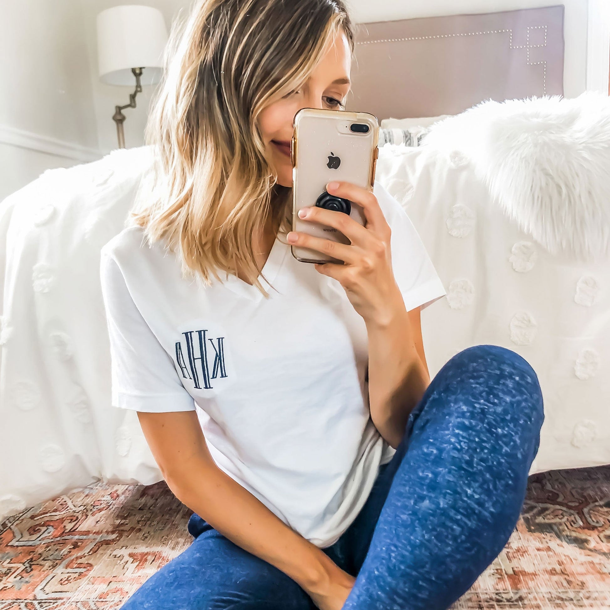 girl taking a selfie in the mirror wearing navy pj pants and a white short sleeved vneck top with custom three letter monogram embroidery in navy thread