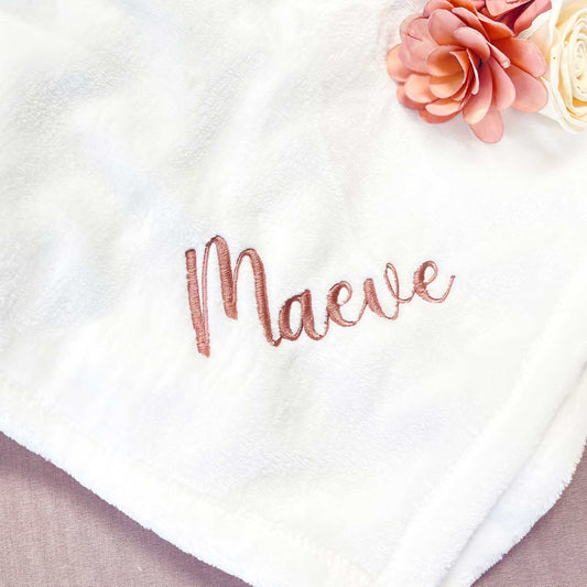 close up of a name embroidered in a script font on the corner of a white fleece blanket