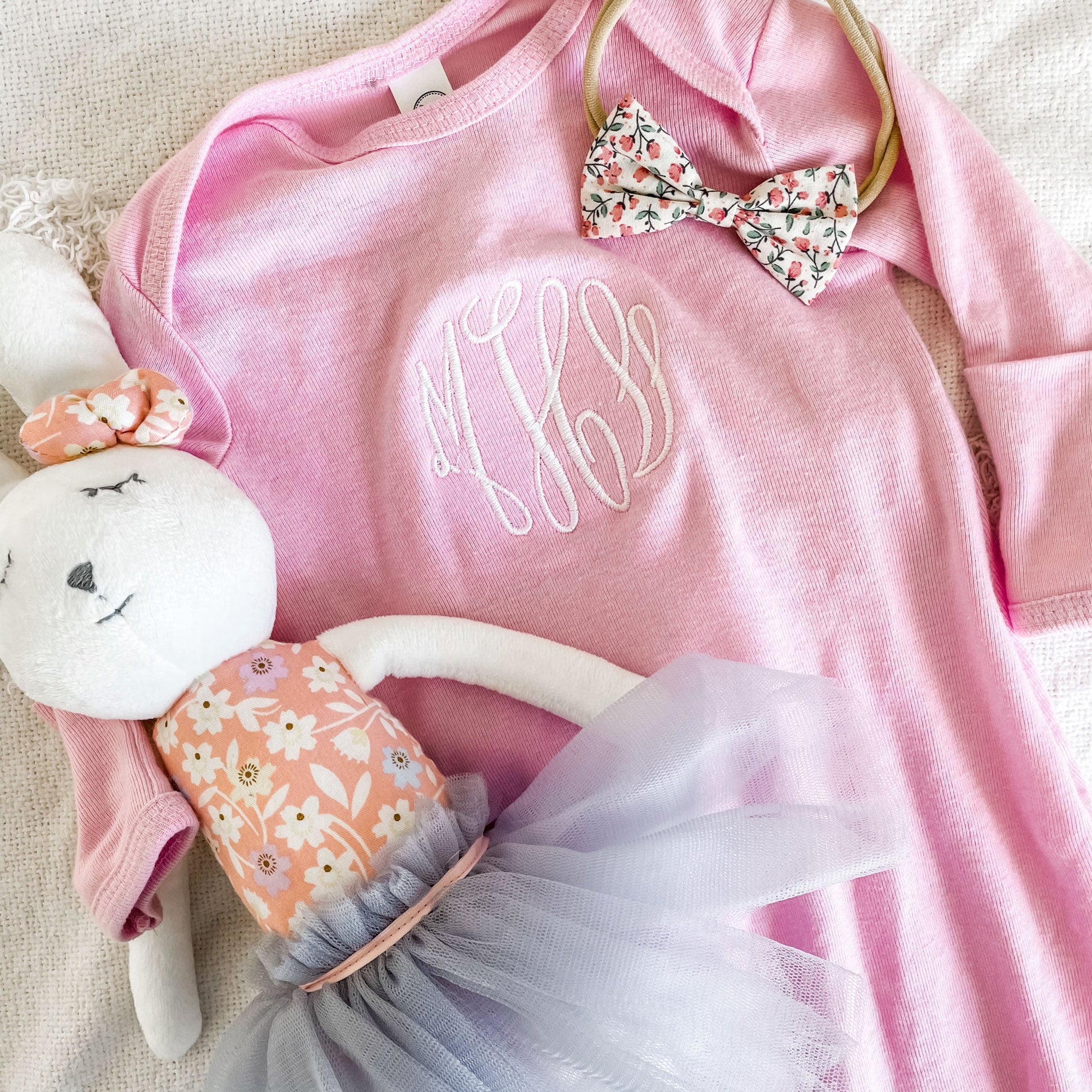flat lay of pink layette with white embroidery