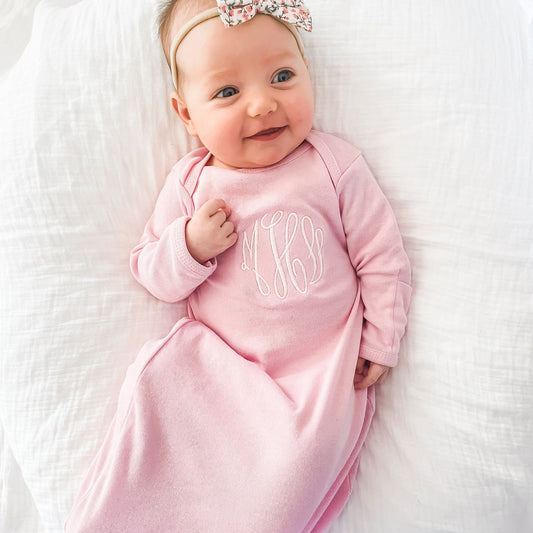 baby with bow smiling wearing pink layette