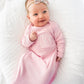 baby with bow smiling wearing pink layette