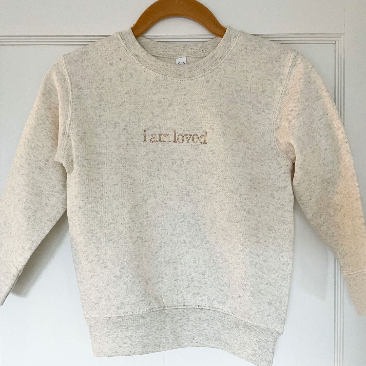 crewneck sweatshirt with i am loved embroidered in lowercase across the chest 