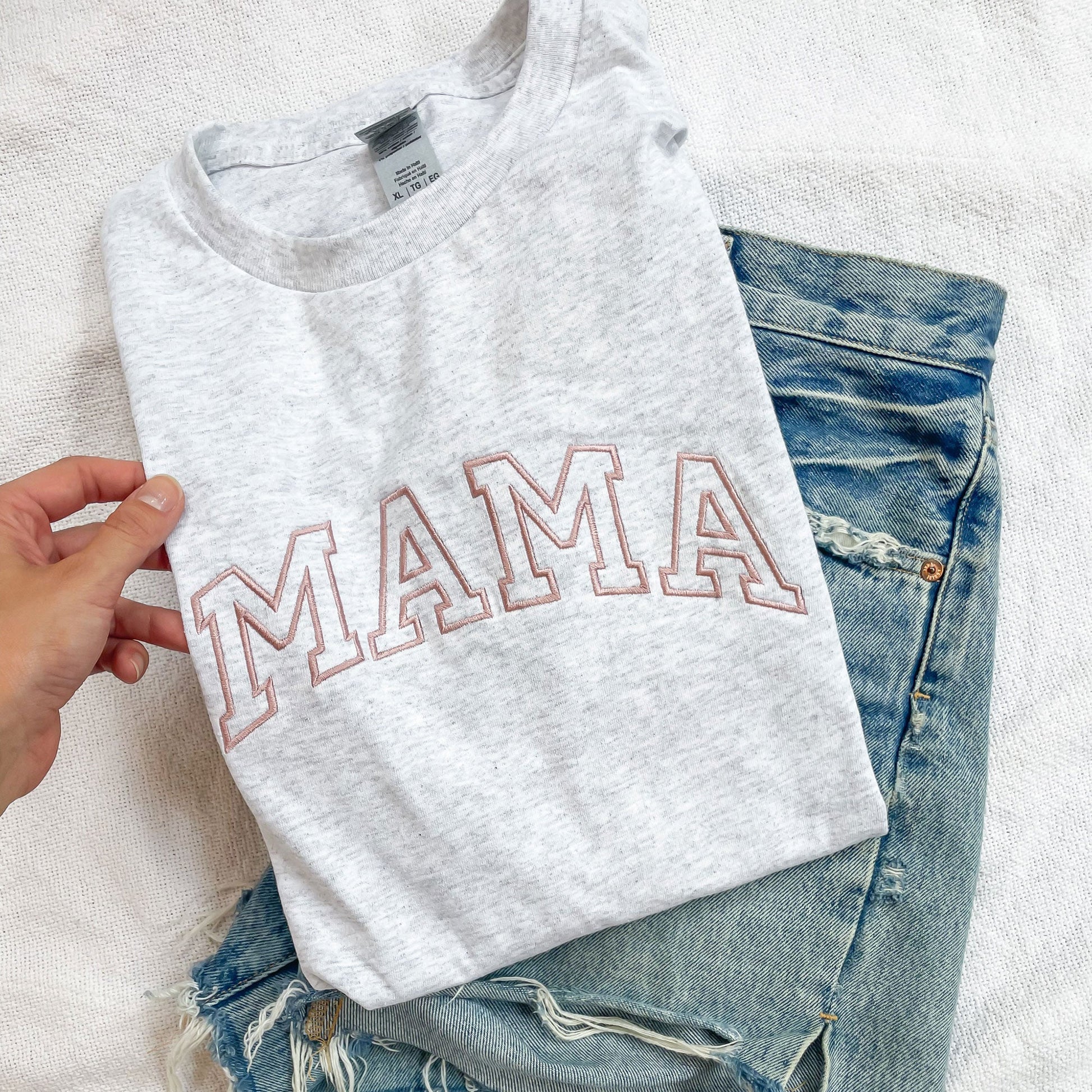 close up of ash gray tee with mama embroidered on the front paired with jean shorts