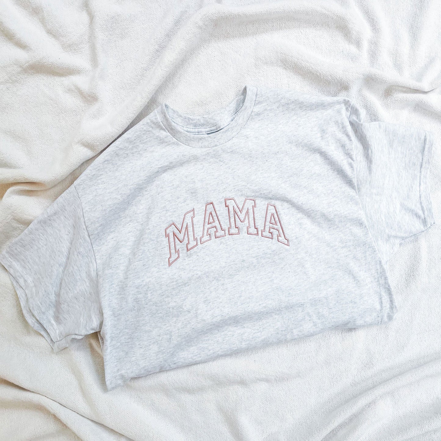 flat lay of gray t-shirt with mama embroidered across the chest in pink thread and in an athletic block font