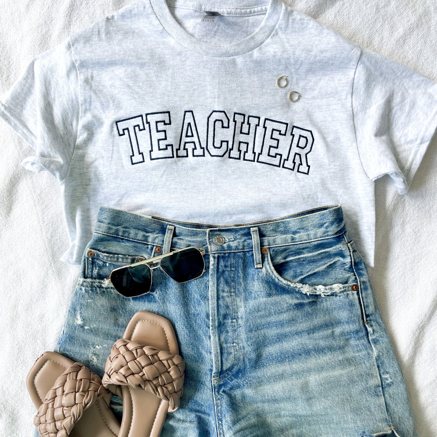 outfit layout for a teacher featuring a t-shirt with teacher embroidered in athletic block font across the chest 