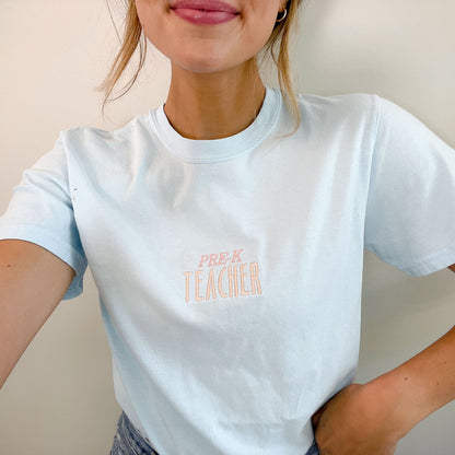 smiling woman wearing chambray shirt with Pre-K Teacher embroidered in center of shirt