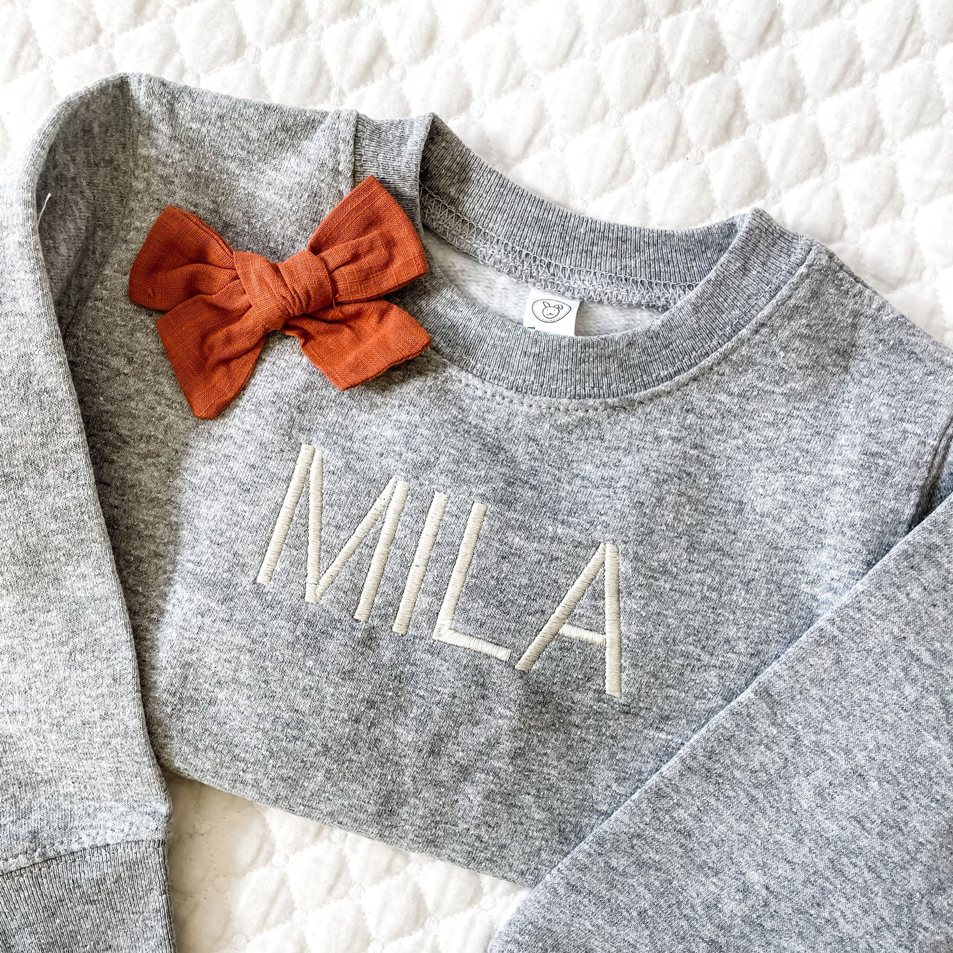 flat lay of short name embroidered across the front of a toddler sweatshirt