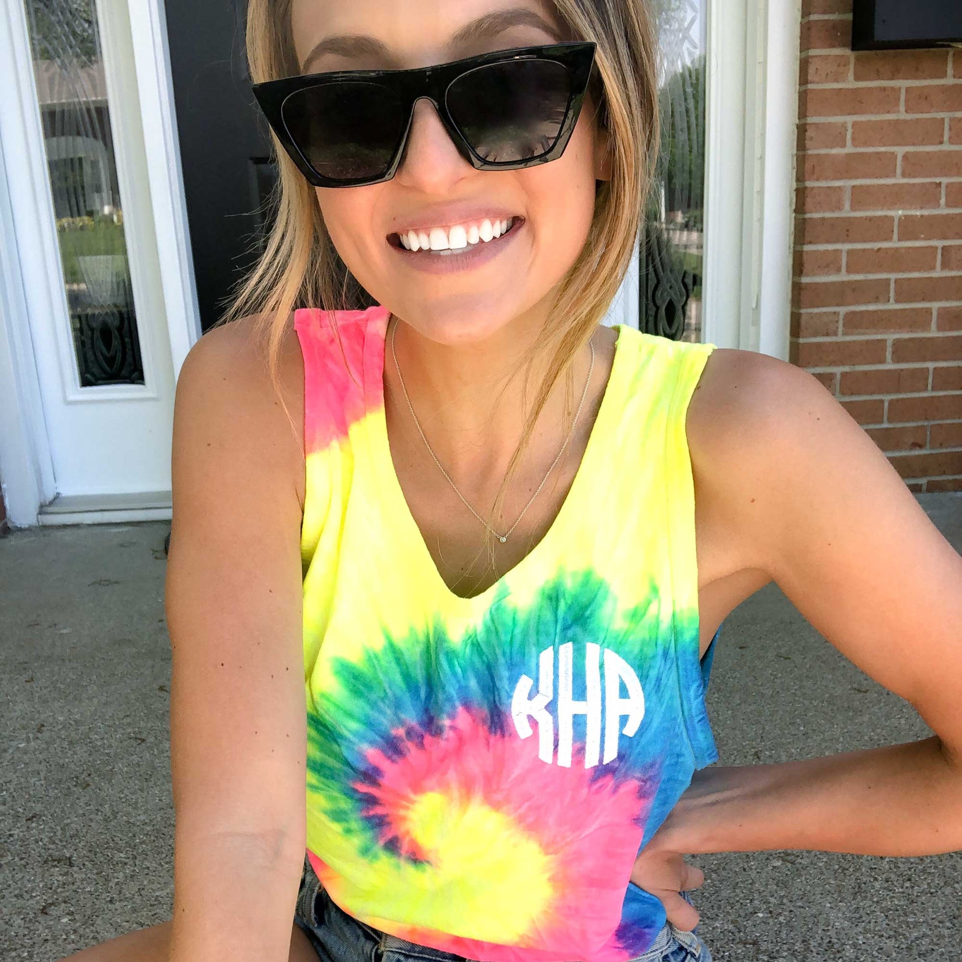 girl wearing a neon tie dye tank top with a circle font white personalized monogram