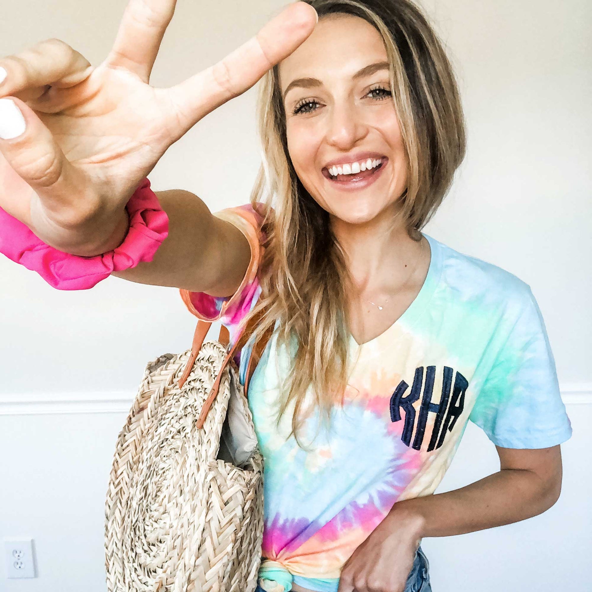 girl wearing a summer outfit, featuring a pastel tie dye v-neck tee with custom monogram embroidery 