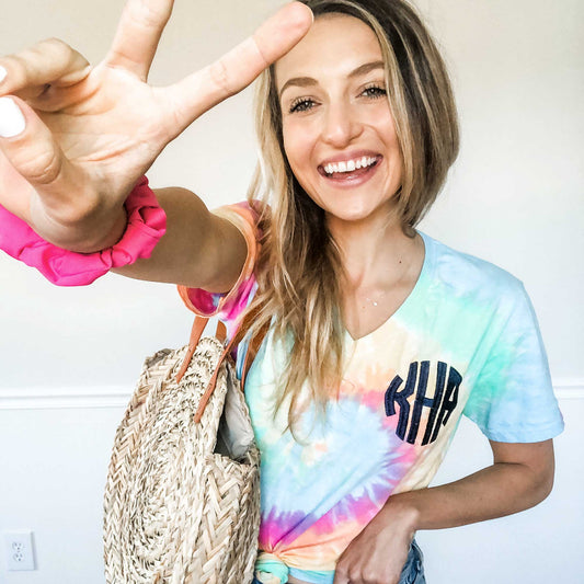 girl wearing a summer outfit, featuring a pastel tie dye v-neck tee with custom monogram embroidery 