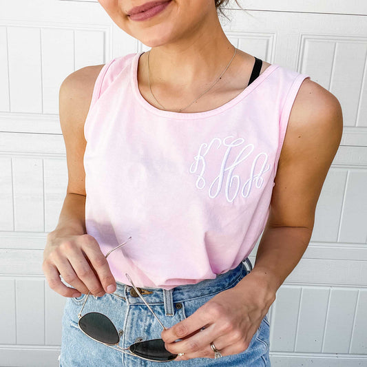 woman wearing  jean shorts and a pink comfort colors tank top with an embroidered three letter monogram
