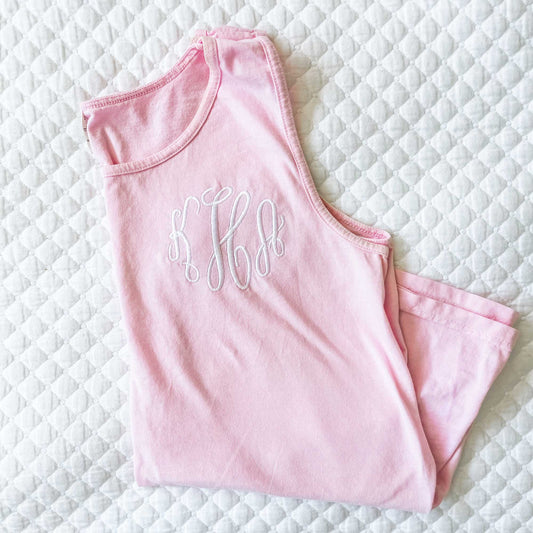 blossom pink tank top with custom monogram embroidery in white thread laying on a white quilt