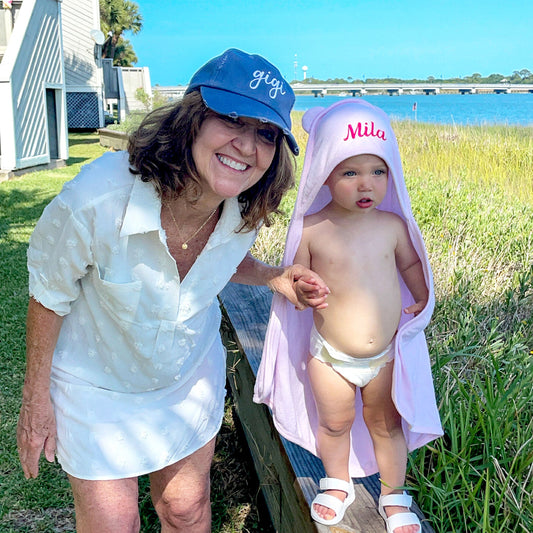 little girl standing with grandmother at beach wearing pink hooded towel with ears