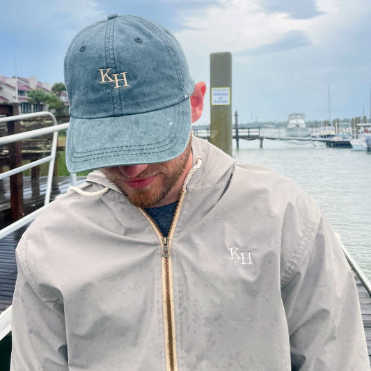 close up of man wearing a vintage style rain coat with a hood and a personalized two letter monogram on the left chest