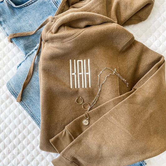 close up of brown hoodie with personalized monogram embroidery in natural thread.