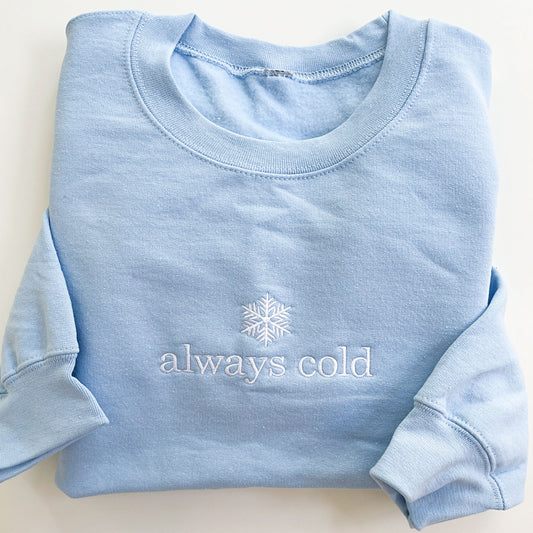light blue crewneck sweatshirt with always cold embroidered on it