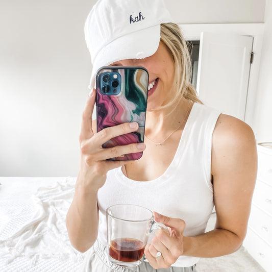 Young woman wearing white small initials baseball hat taking mirror selfie