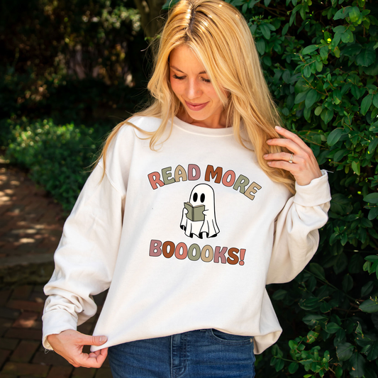 woman wearing an oversized cream sweatshirt with a coloful 'read more boooks!' ghost print design