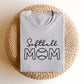 image of a heather gray t-shirt with a printed design reading 'softball' in a script font and 'mom' in an open block font with a baseball in place of the 'o'