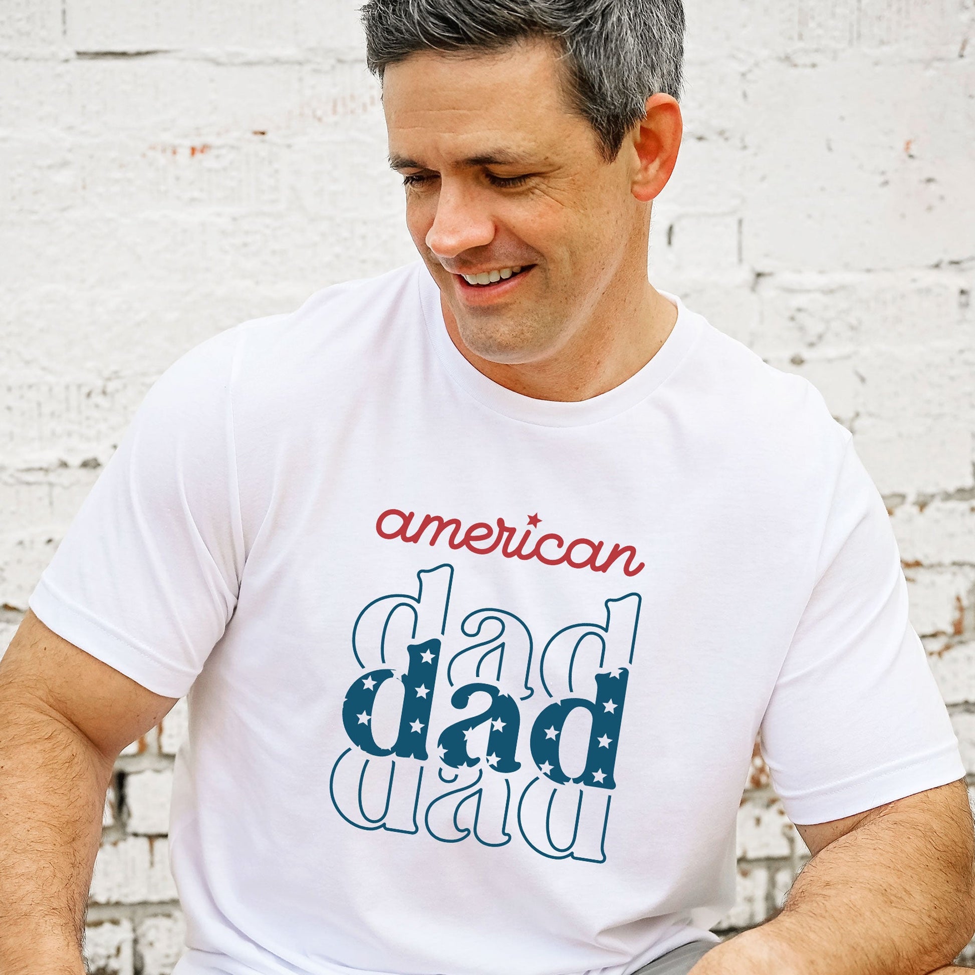 man wearing a white t-shirt featuring a red, white, and blue 'american dad' patriotic print