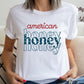 woman wearing a white t-shirt featuring an 'american honey' red white and blue patriotic print