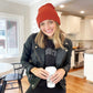 woman wearing a black leather jacket and a rust colored waffle knit beanie